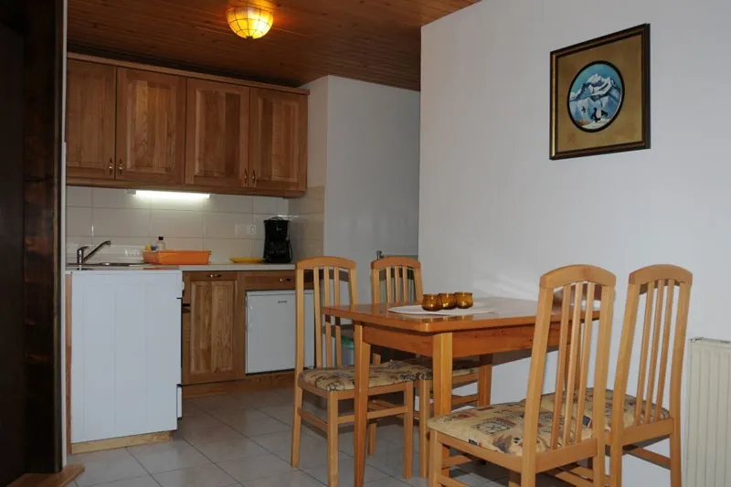 Apartma 3: kuhinja z lesenimi omaricami in jedilno mizo