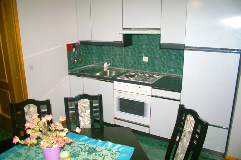 Kuhinja Apartmaja 6 z zelenimi ploščicami in jedilno mizo