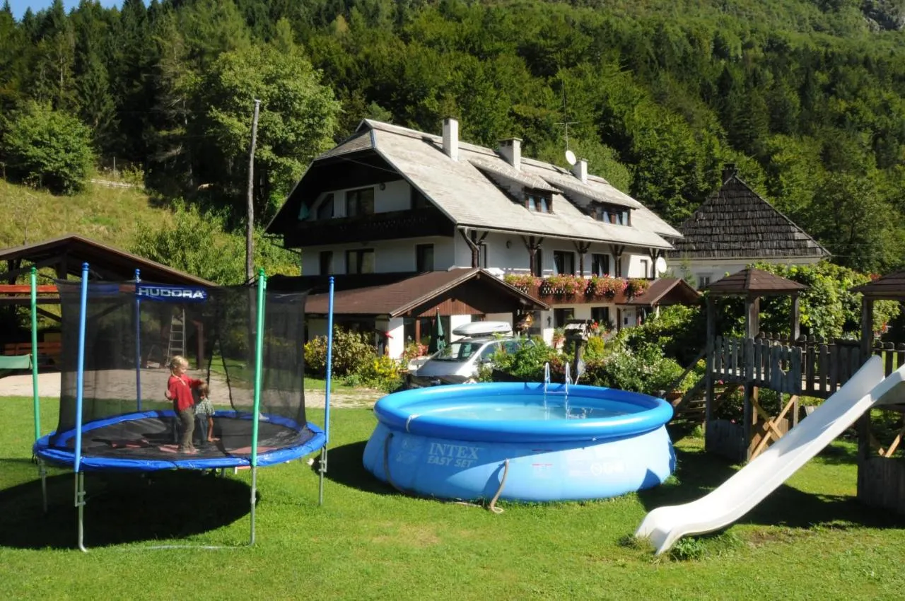 Hiša Apartmajev Rabič z balkoni, pred njo vrt s trampolinom, bazenom in toboganom